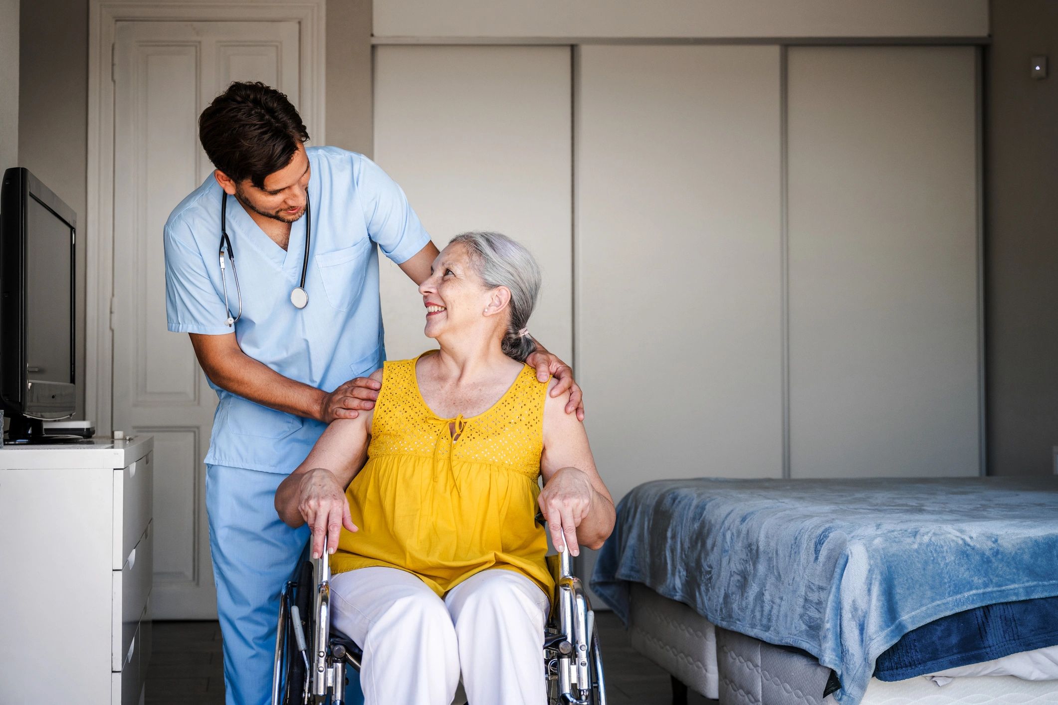 Healthcare professional supporting a senior patient in a wheelchair